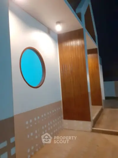 Modern architectural exterior with unique circular window and wood paneling at night.