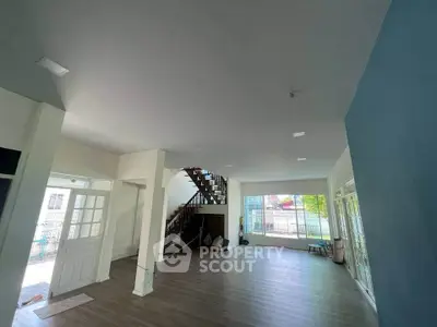 Spacious open-plan living room with large windows and modern staircase