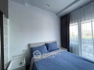 Cozy bedroom with modern decor and large window offering natural light and city view.