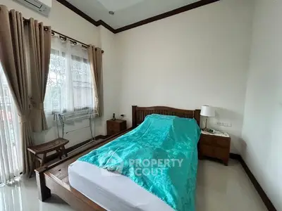 Cozy bedroom with wooden furniture and large window for natural light