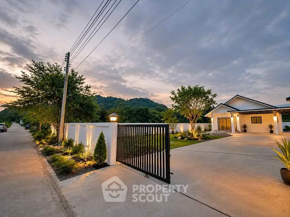 Stunning modern home with gated entrance and scenic mountain views at dusk.