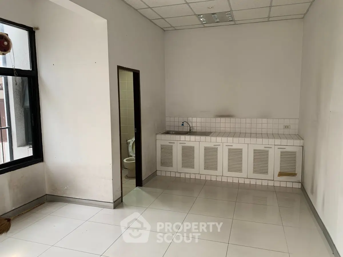 Spacious room with tiled floor and kitchenette, ideal for versatile use.