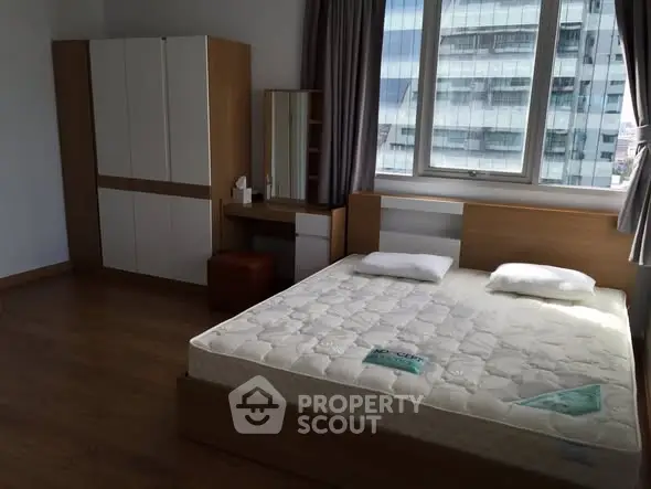 Spacious bedroom with modern furniture and large window view.