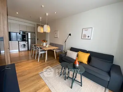 Modern living room with open kitchen, stylish decor, and wooden flooring.