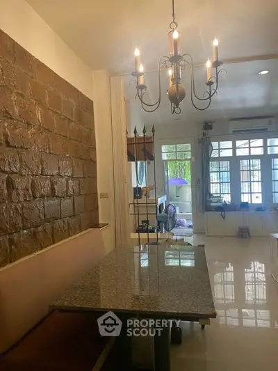 Charming dining area with brick accent wall and elegant chandelier lighting.
