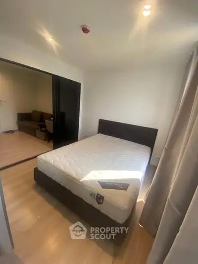 Cozy bedroom with natural light and sliding doors leading to a living area, perfect for modern living.