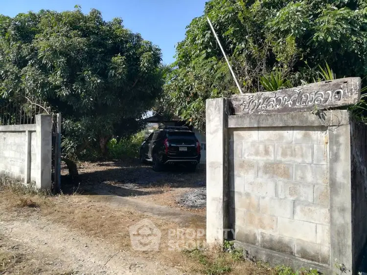 Charming gated entrance with lush greenery and parked car, perfect for privacy and tranquility.
