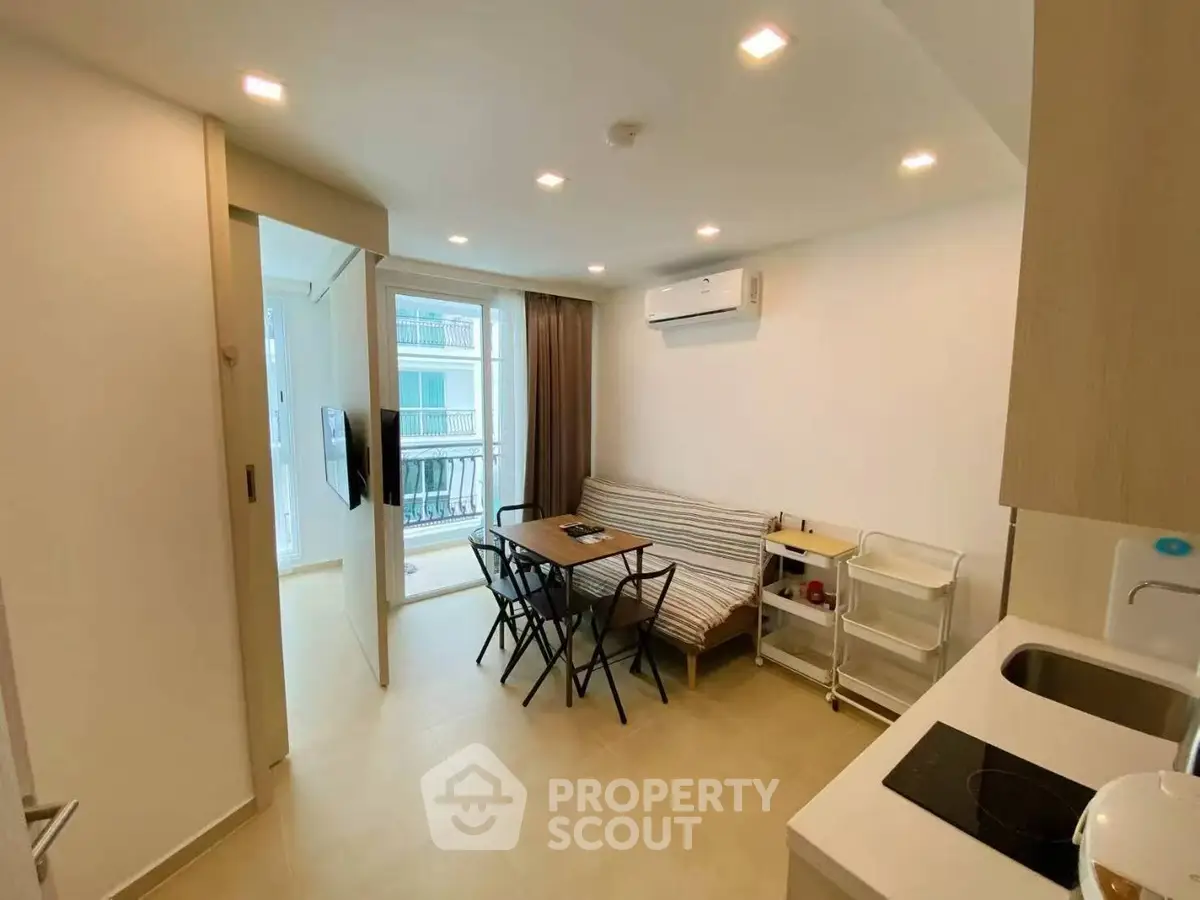 Modern open-layout living room with dining area and balcony access in a stylish apartment.