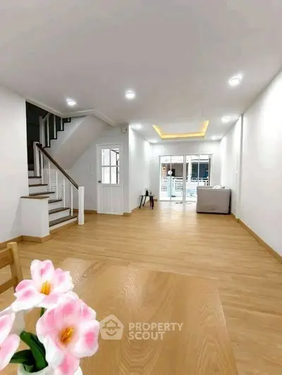 Spacious modern living room with wooden flooring and staircase, perfect for family gatherings.
