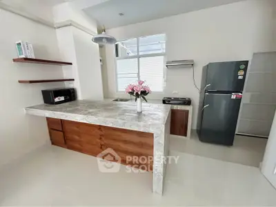 Modern kitchen with sleek countertops, stainless steel fridge, and open layout design.