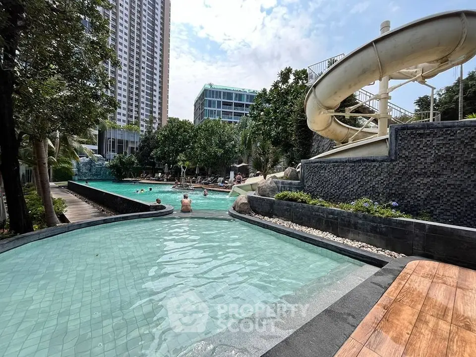 Luxurious pool area with water slide and lush greenery in modern residential complex.
