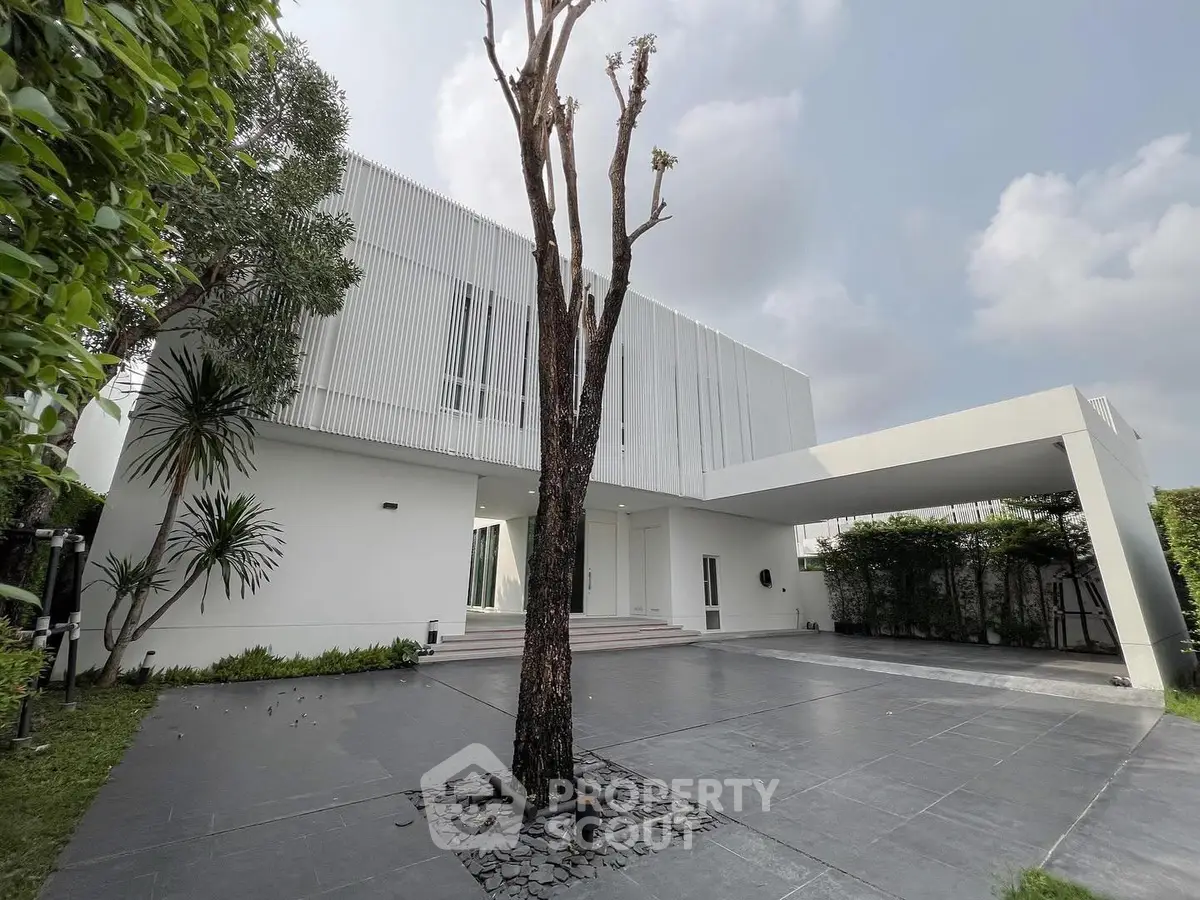 Modern minimalist white house with spacious driveway and lush greenery