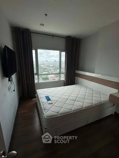 Modern bedroom with city view, featuring a large window, wall-mounted TV, and stylish decor.