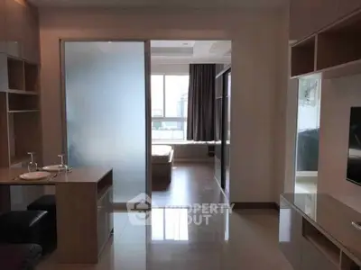 Modern studio apartment with sleek design and ample natural light, featuring a frosted glass partition and stylish furnishings.