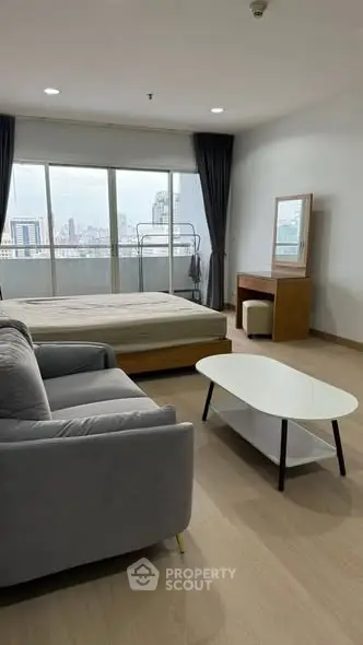 Spacious studio apartment with city view, featuring modern furniture and large windows.
