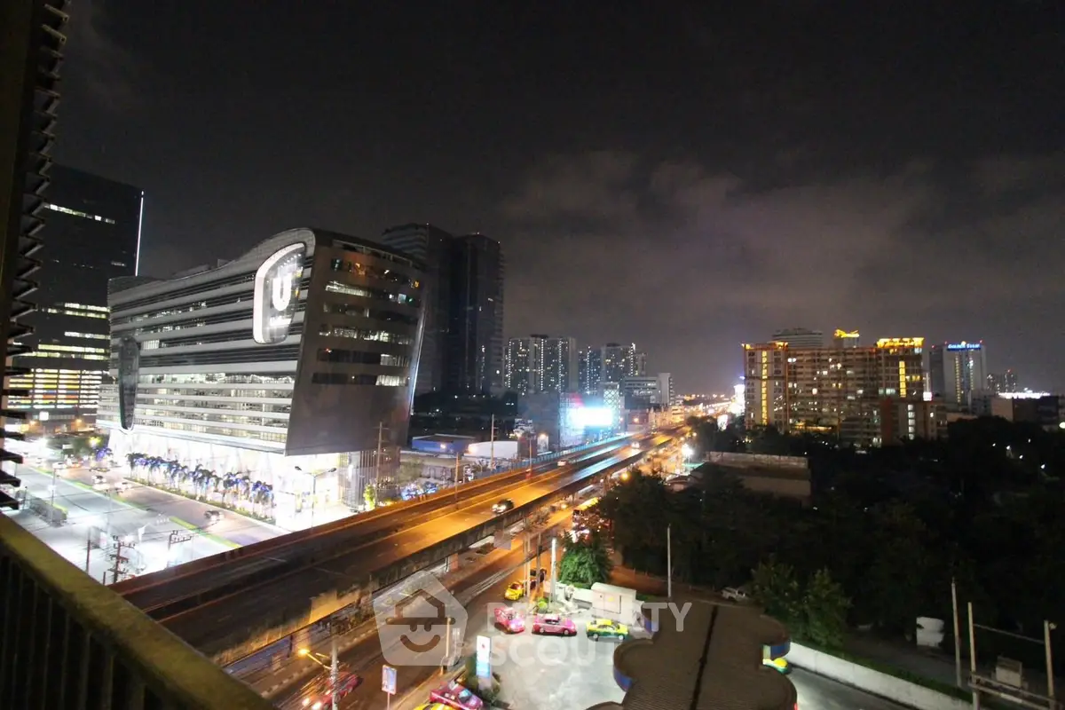 Stunning night cityscape view from a high-rise balcony overlooking vibrant city lights and modern architecture.