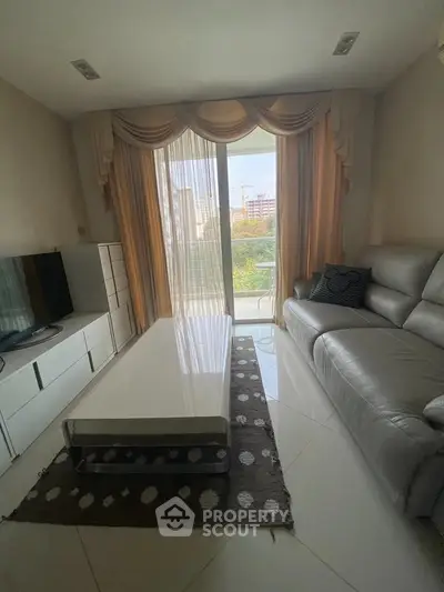 Modern living room with sleek furniture and large window offering natural light.