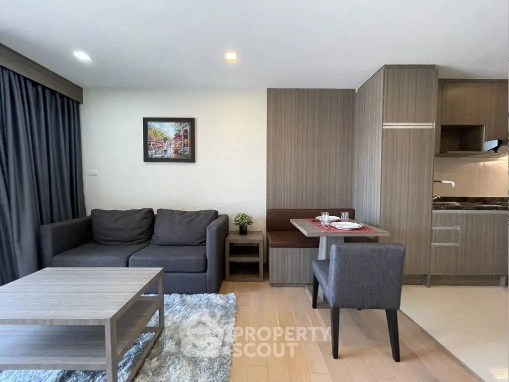 Modern living room with cozy seating and stylish kitchen in open layout apartment.