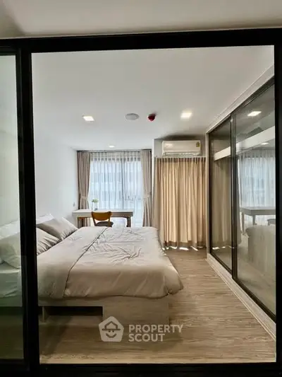 Modern bedroom with large window and stylish decor in a contemporary apartment.
