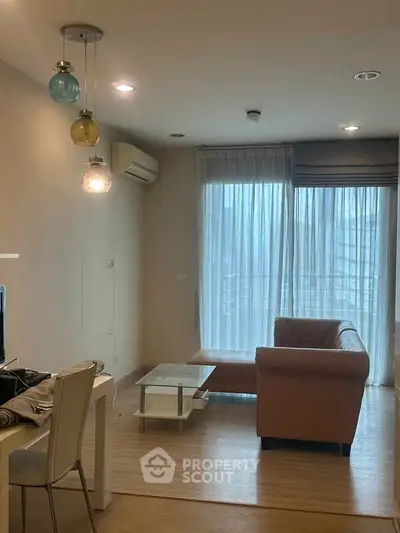 Modern living room with cozy sofa and stylish lighting, featuring a large window with sheer curtains.