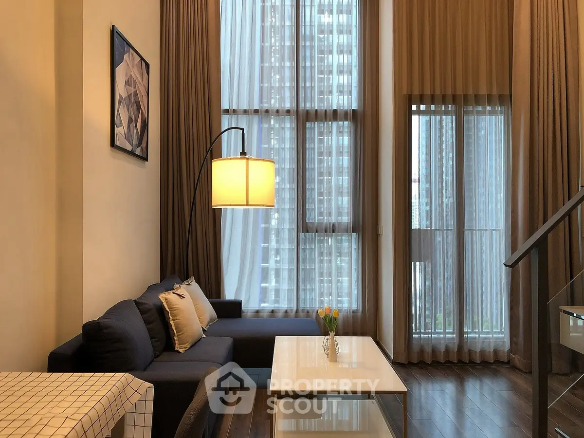 Modern living room with high ceilings and large windows in urban apartment.