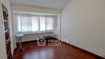 Spacious living room with wooden flooring and large windows for natural light.