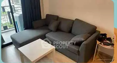 Cozy living room with modern gray sofa and white coffee table near balcony.