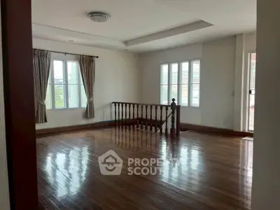 Spacious and bright living room with polished wooden floors and large windows.
