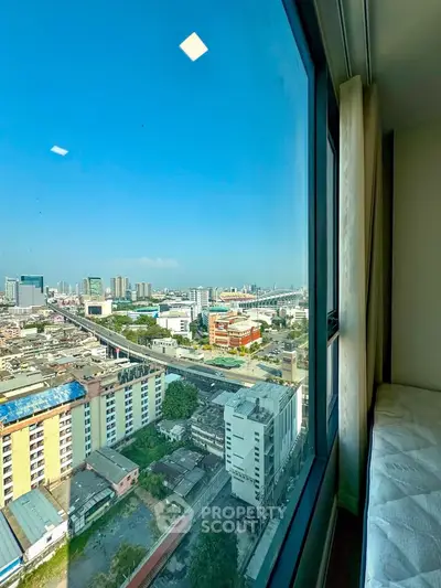 Stunning cityscape view from high-rise apartment window, showcasing urban skyline and clear blue sky.