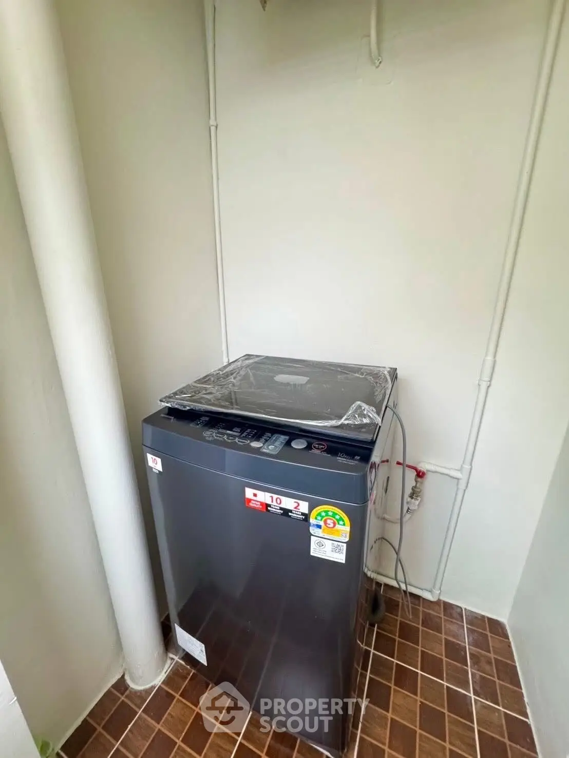 Compact laundry area with modern washing machine in tiled corner space.