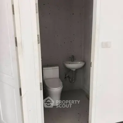 Compact bathroom with modern toilet and wall-mounted sink in minimalist design.