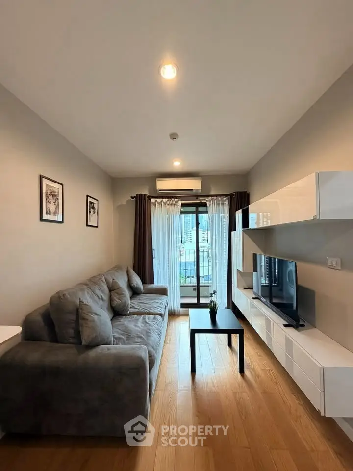 Modern living room with cozy sofa and sleek TV unit, featuring a balcony view.