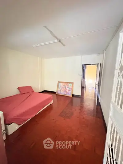 Spacious bedroom with wooden flooring and minimalist decor, perfect for personalization.