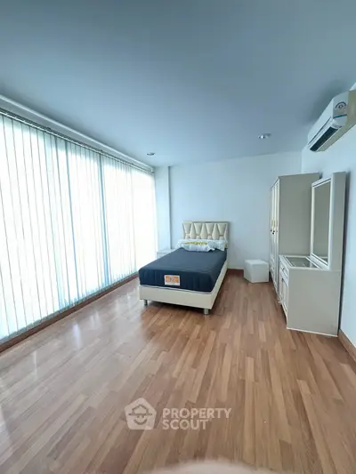 Spacious bedroom with modern furnishings and large windows for natural light.