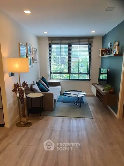 Modern living room with stylish decor, large window, and cozy seating area.