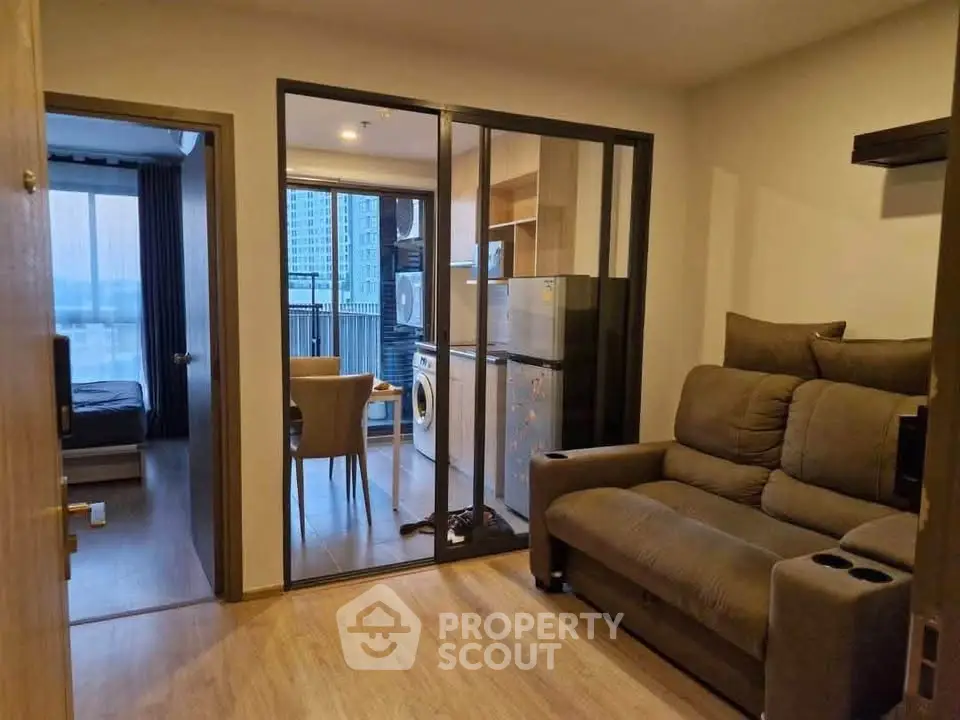 Modern apartment interior with cozy living room and glass partitioned dining area.