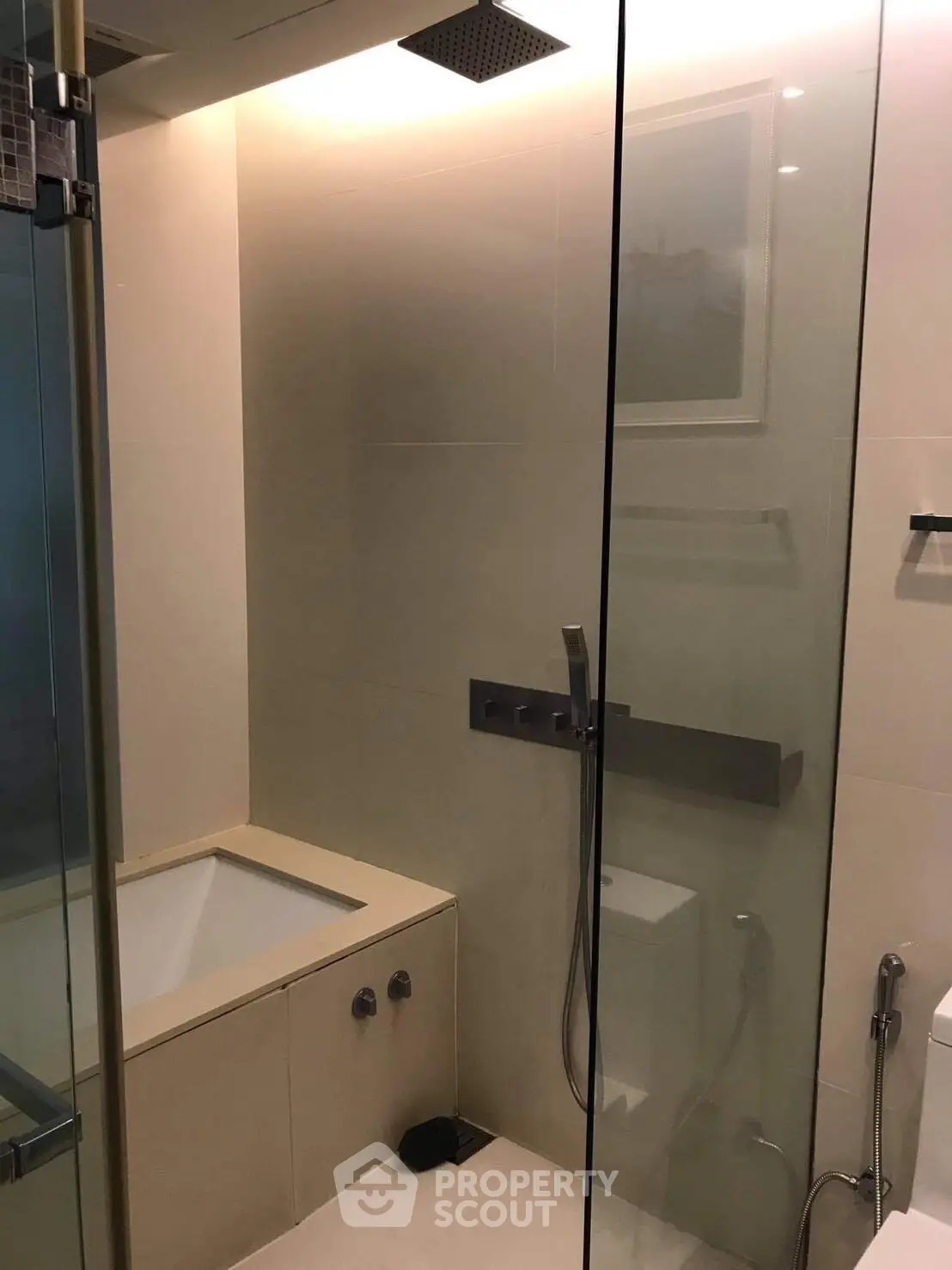 Modern bathroom with glass shower and built-in bathtub in luxury apartment.