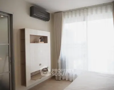 Modern bedroom with sleek air conditioning and natural light through sheer curtains.