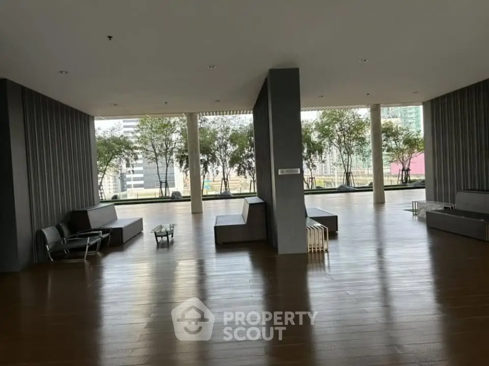 Spacious modern building lobby with wooden flooring and outdoor view.