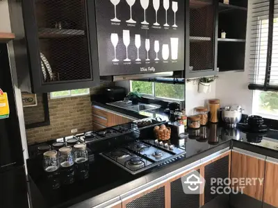 Modern kitchen with sleek black countertops and gas stove, featuring stylish cabinetry and ample natural light.