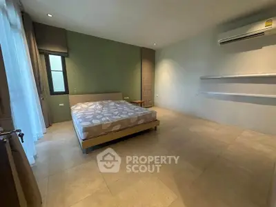 Spacious bedroom with modern design and air conditioning, featuring a comfortable bed and ample natural light.