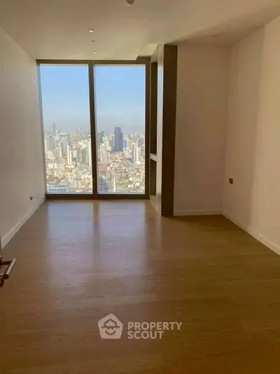 Spacious room with floor-to-ceiling windows offering stunning city skyline views.