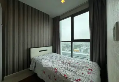 Cozy bedroom with large window offering city view, featuring modern decor and comfortable bedding.