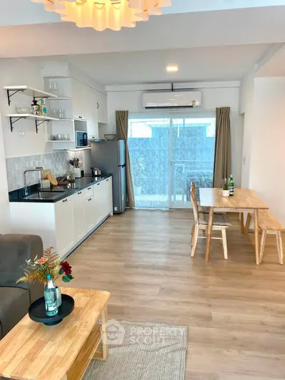 Modern open-plan living room and kitchen with wooden flooring and stylish furniture.