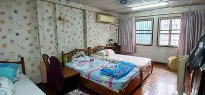 Cozy bedroom with twin beds and floral wallpaper, featuring large windows and wooden flooring.