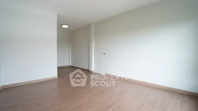 Spacious empty room with wooden flooring and white walls, ideal for customization.
