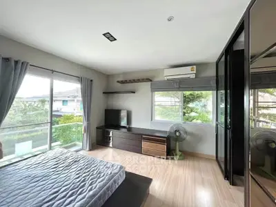 Spacious bedroom with large windows and modern furnishings, offering a serene view.