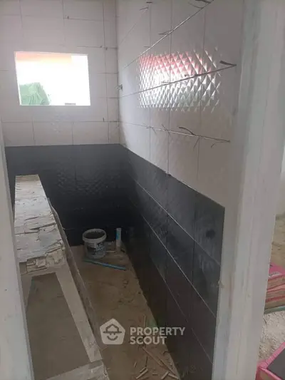 Under-construction bathroom with tiled walls and window