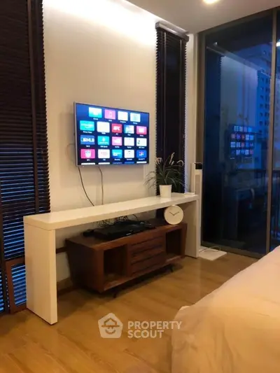 Modern bedroom with sleek TV setup and wooden flooring, perfect for urban living.