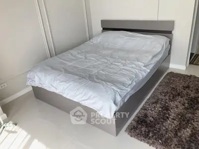 Modern bedroom with sleek bed and cozy rug in a stylish apartment.